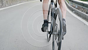 Skinny fit cyclist legs with strong muscles pedaling uphill out of the saddle. Cycling training uphill. Cycling concept. Slow moti