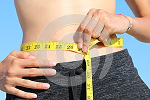 Skinny girl measures your waist with a flexible tape measure and measures in inches