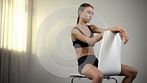 Skinny girl sitting on chair, exhausted by malnourishment, anorexia, depression