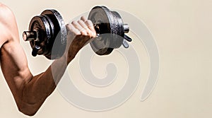 Skinny guy hold dumbbells up in hands. Thin man in sports with dumbbells. Weak man lift a weight, dumbbells, biceps