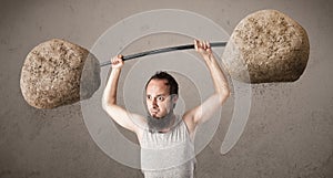 Skinny guy lifting large rock stone weights