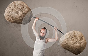 Skinny guy lifting large rock stone weights