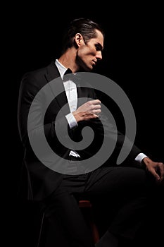 Skinny man in black with bowtie posing in dark studio