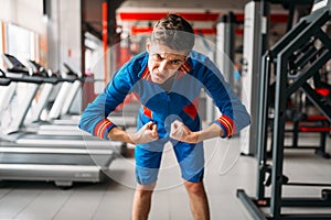 Skinny man in sportswear shows his muscles, gym