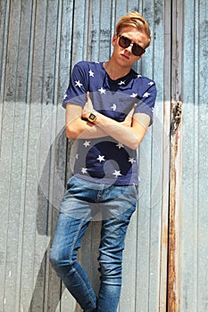 Skinny man standing against metal wall with hands crossed