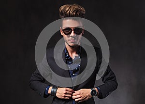 Skinny model posing in dark studio background wearing sunglasses