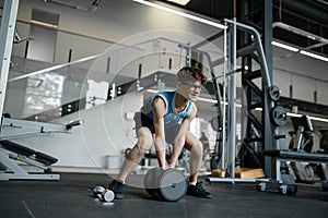 Skinny nerd wimp trying to lift heavy dumbbells at gym