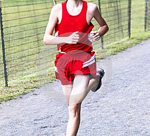 Skinny runner running on a gravel path during a cross country race