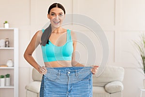 Skinny Woman Comparing Oversize Jeans After Weight Loss At Home photo