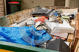 Skip bin full of household waste rubbish on the front yard