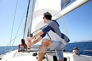 Skipper navigating the sailing boat, woman relaxing