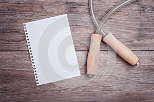 Skipping rope and lined paper on wooden table top view
