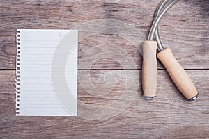 Skipping rope and lined paper on wooden table top view