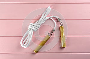 Skipping rope on pink wooden table, top view. Sports equipment
