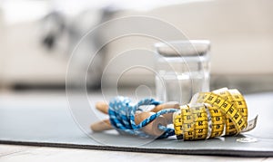 A skipping rope, a tape measure and a glass of water on a mat at home in the living room. Concept of healthy lifestyle