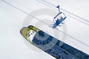 Skis above skiers shadows in chairlift above the white snow, during a Winter ski vacation in Les Sybelles, French Alps.