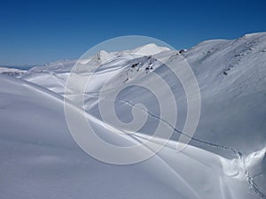 Skitouring trail in white snow covered mountains