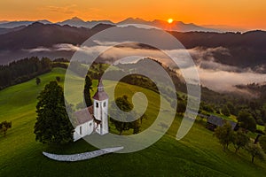 Skofja Loka, Slovenia - Aerial panoramic view of the beautiful hilltop church of Sveti Tomaz Saint Thomas with golden sunrise