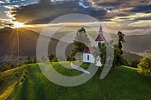 Skofja Loka, Slovenia - Aerial view of the beautiful hilltop Sveti Tomaz Saint Thomas church with a warm summer sunset