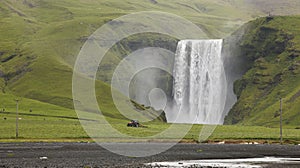 Skogafoss waterfall and tractor plowing field. Iceland. South ar