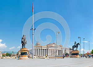 Undefined tourists visit Skopje center, square Macedonia. View of Stone Bridge approach, Archeological museum and two worrior stat