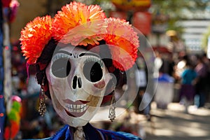 Skull painted and decorated with orange paper mache flowers and earrings/decorated skull for Dia de los Muertos, Day of the Dead