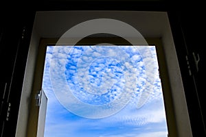 Sky with altocumulus floccus clouds through the window