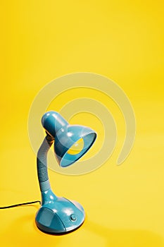 Sky-blue desk lamp on yellow background.