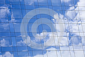 Sky and clouds background reflected on the glass mirror surface of a modern building