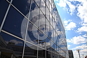 Sky with clouds casted in a glass facade of a building