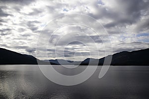 The sky in the clouds over the mountains and the fjord