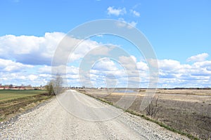 Sky, clouds, river. Village road. Far village and forest. A large field of young grass, boundless. Agricultural