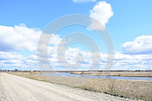 Sky, clouds. Road to the village. River. Fields of young grass. Agricultural