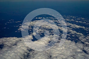 The sky and clouds and the view seen in the window of the plane.