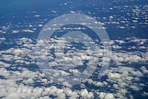 The sky and clouds and the view seen in the window of the plane.