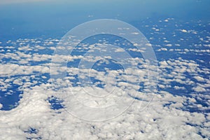 The sky and clouds and the view seen in the window of the plane.