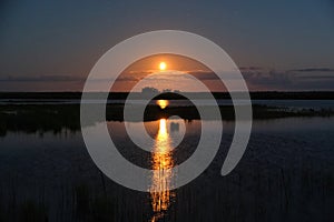 Moon set observingn over lake in Latvia photo