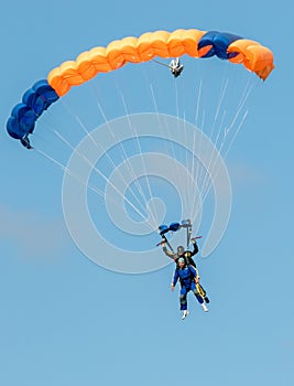 Sky diving tandem parachutists gliding toward landing