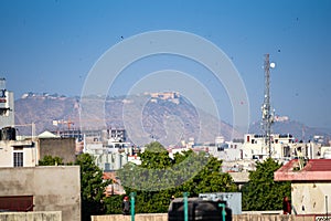 sky filled with kites with aravalli mountains hills with nahargarh fort in background showing celebrations of makar