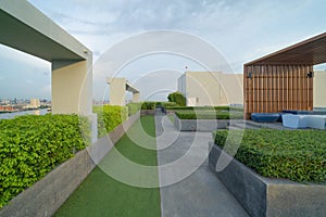 Sky garden on private rooftop of condominium or hotel, high rise architecture building with tree, grass field, and blue sky