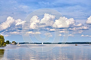 Sky with gigantic clouds over a lake with sailing boats and motor boats