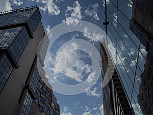 The sky and glass facade of the building. Reflection of the blue sky and white clouds on the glass wall. City