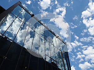 The sky and glass facade of the building. Reflection of the blue sky and white clouds on the glass wall. City