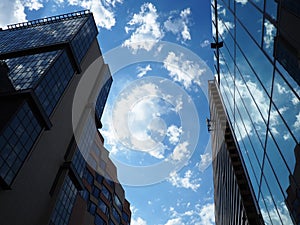 The sky and glass facade of the building. Reflection of the blue sky and white clouds on the glass wall. City