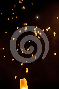 Sky lanterns, flying lanterns, floating lanterns, hot-air balloons on dark night sky with moon. New year and Yeepeng festival photo