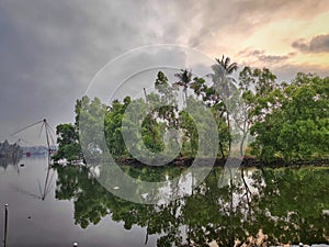 the sky is low over trees and water on the shore