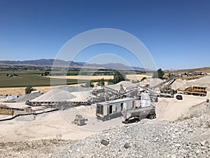 Aggregate rock crushing plant set up in with conveyors and screening plant and crusher and jaw.  Beautiful summer sky.