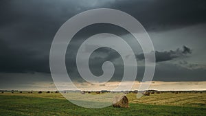 Sky before rain with rain clouds on horizon above rural landscape field meadow with hay bales after harvest. time lapse