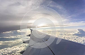 Sky scape view from clear glass window seat to the aircraft wing of the plane, traveling on the clouds and sunshine with blue sky