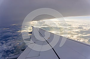 Sky scape view from clear glass window seat to the aircraft wing of the plane, traveling on the clouds and sunshine with blue sky